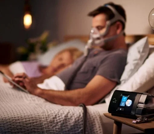 Barbat citind in pat cu Aparat Auto CPAP, AirSense 10 AutoSet cu umidificator, ResMed