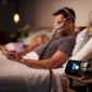 Barbat citind in pat cu Aparat Auto CPAP, AirSense 10 AutoSet cu umidificator, ResMed