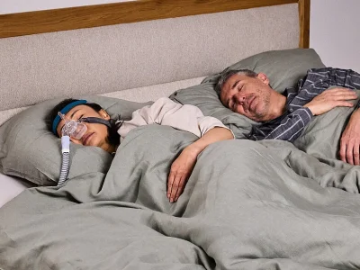 alergii si apnee in somn, cuplu adult dormind, femeie tanare cu aparat si masca petnru apnee