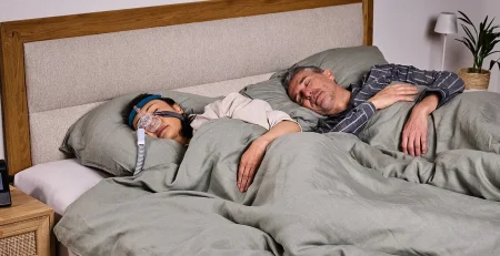 alergii si apnee in somn, cuplu adult dormind, femeie tanare cu aparat si masca petnru apnee