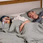 alergii si apnee in somn, cuplu adult dormind, femeie tanare cu aparat si masca petnru apnee
